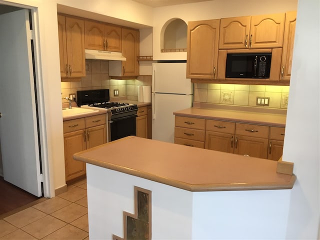 kitchen featuring sink, gas stove, tasteful backsplash, light tile patterned floors, and white refrigerator