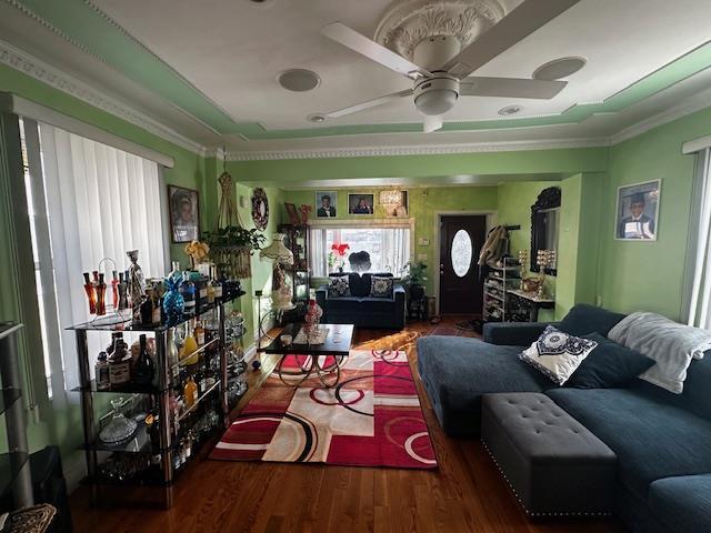 living room featuring crown molding, wood-type flooring, and ceiling fan