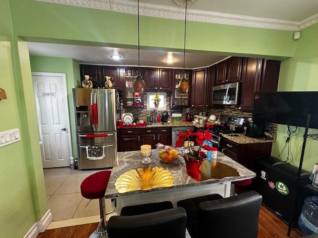 kitchen featuring stone counters, tasteful backsplash, hanging light fixtures, a center island, and stainless steel appliances