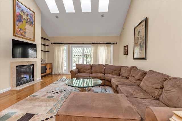 living room featuring hardwood / wood-style floors, built in shelves, a skylight, and high vaulted ceiling