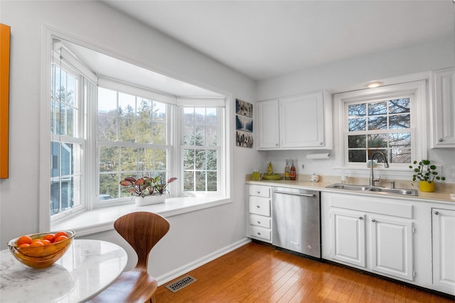 kitchen with white cabinetry, light hardwood / wood-style floors, dishwasher, and sink