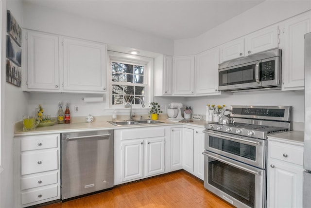 kitchen featuring white cabinetry, sink, light hardwood / wood-style flooring, and appliances with stainless steel finishes