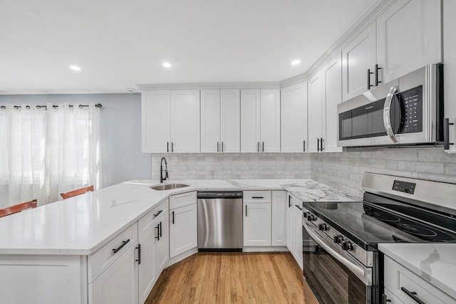 kitchen featuring stainless steel appliances, white cabinetry, and light stone countertops