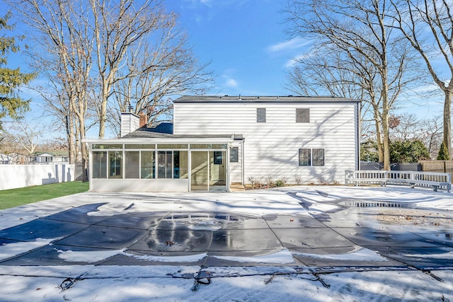 snow covered house with a patio area and a sunroom