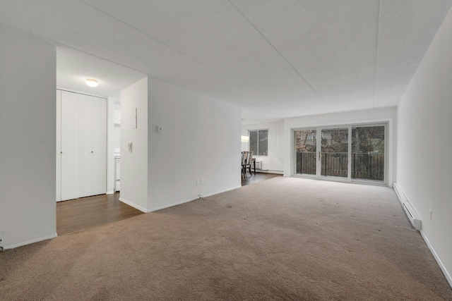 spare room with dark carpet and a baseboard radiator