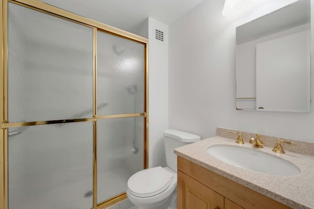 bathroom featuring vanity, a shower with shower door, and toilet