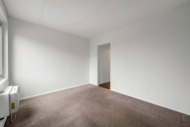 unfurnished room featuring dark colored carpet