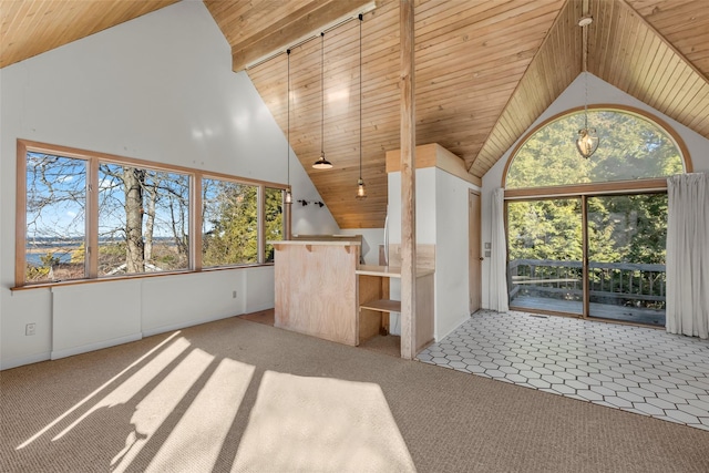 unfurnished living room with a healthy amount of sunlight, light colored carpet, wood ceiling, and high vaulted ceiling