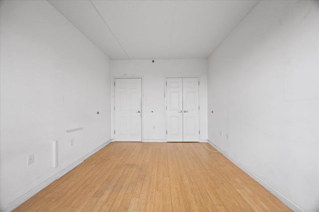 unfurnished bedroom with multiple closets and light hardwood / wood-style flooring