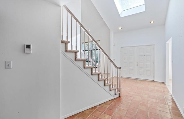 tiled entryway with a skylight and a high ceiling