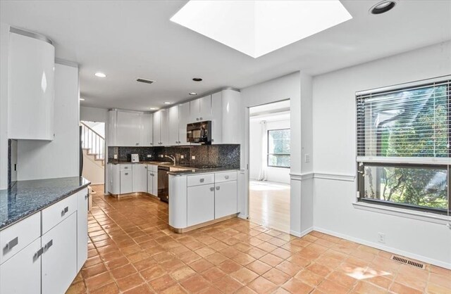 kitchen with dark stone countertops, tasteful backsplash, black appliances, white cabinets, and light tile patterned flooring