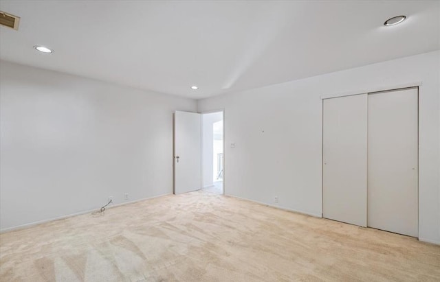 unfurnished bedroom featuring light carpet and a closet