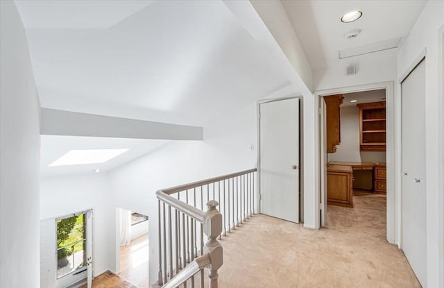 corridor featuring lofted ceiling with skylight and light carpet