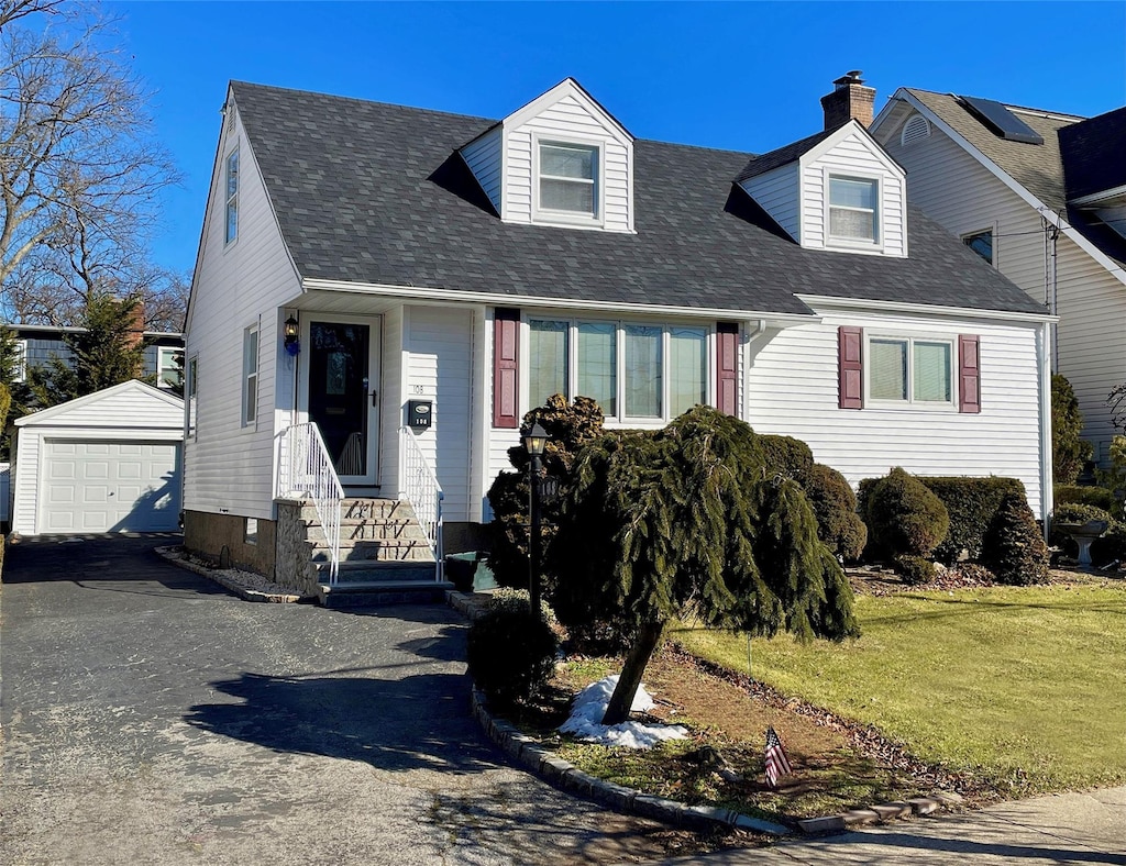 new england style home with a garage, an outdoor structure, and a front lawn