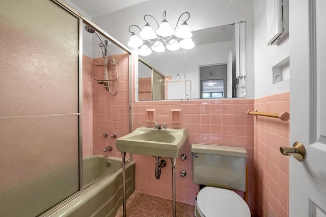 full bathroom featuring bath / shower combo with glass door, toilet, sink, and tile walls