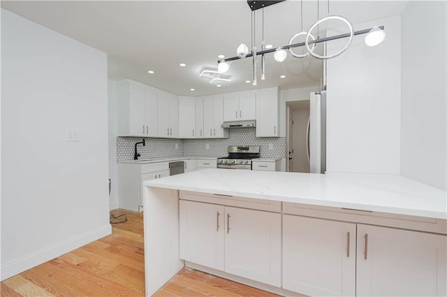 kitchen with stainless steel appliances, white cabinetry, tasteful backsplash, and decorative light fixtures