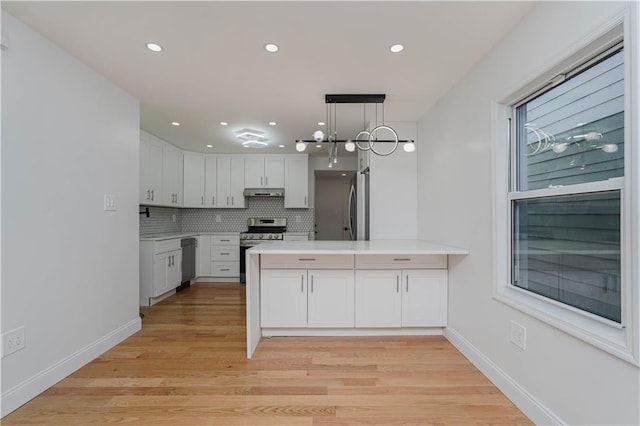 kitchen featuring appliances with stainless steel finishes, white cabinets, backsplash, kitchen peninsula, and light wood-type flooring