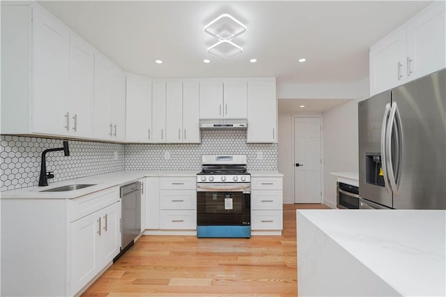 kitchen featuring sink, light hardwood / wood-style flooring, appliances with stainless steel finishes, backsplash, and white cabinets