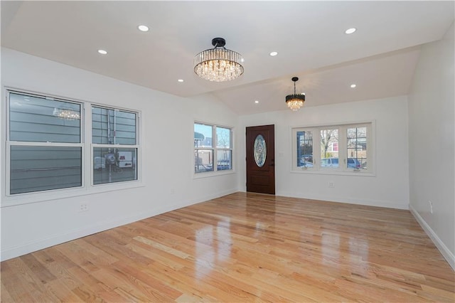 entrance foyer featuring vaulted ceiling, light hardwood / wood-style flooring, and a notable chandelier