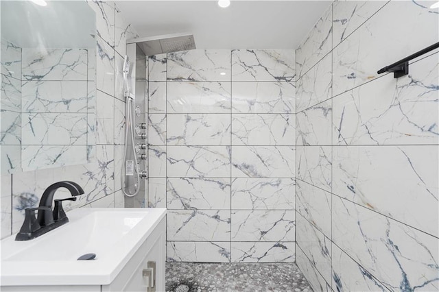 bathroom with vanity, tiled shower, and tile walls