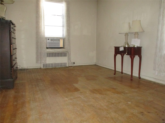 spare room featuring hardwood / wood-style flooring, radiator, and cooling unit