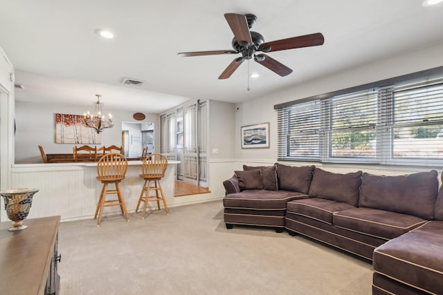 living room with ceiling fan with notable chandelier and light colored carpet