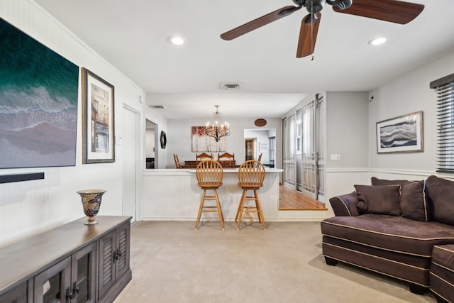 living room with light carpet and ceiling fan with notable chandelier