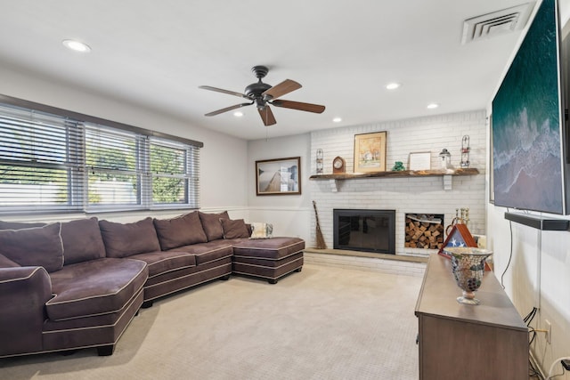 living room with a fireplace, light colored carpet, and ceiling fan