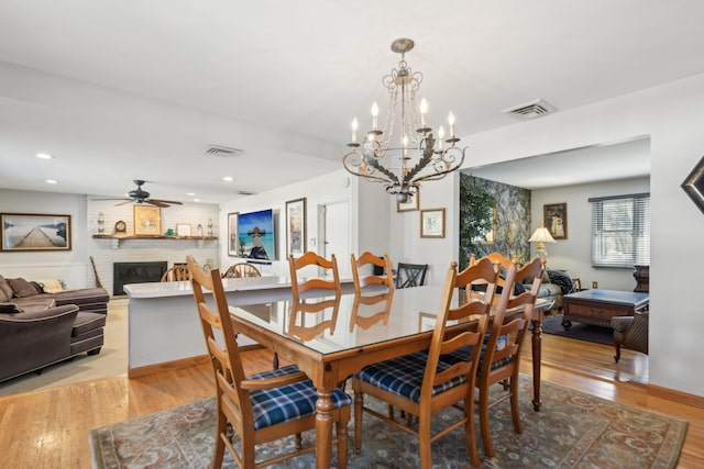 dining area with a fireplace, light hardwood / wood-style floors, and ceiling fan