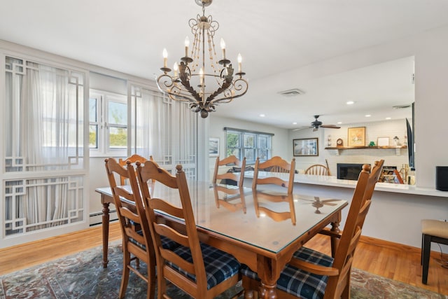 dining room featuring a baseboard heating unit, a fireplace, light hardwood / wood-style floors, and ceiling fan