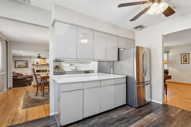 kitchen featuring appliances with stainless steel finishes, sink, gray cabinetry, dark hardwood / wood-style flooring, and ceiling fan