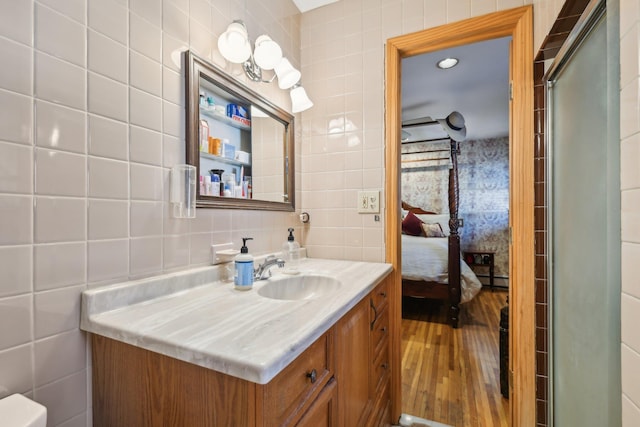 bathroom with hardwood / wood-style flooring, tasteful backsplash, vanity, and tile walls