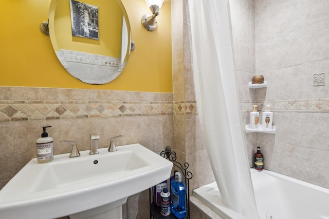 bathroom featuring sink, shower / bath combo with shower curtain, and tile walls