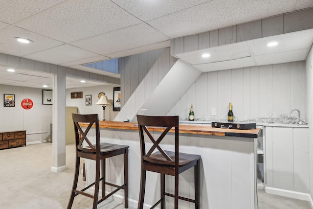 kitchen featuring white cabinetry, sink, a breakfast bar area, wooden counters, and light colored carpet