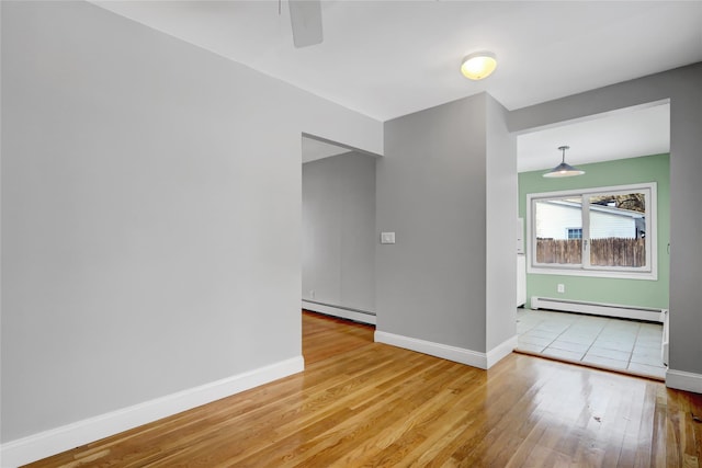 unfurnished room with ceiling fan, a baseboard heating unit, and light wood-type flooring