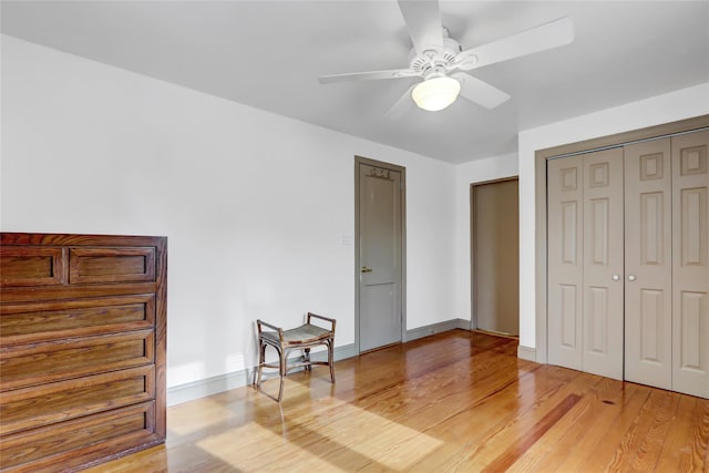 bedroom with light hardwood / wood-style flooring, ceiling fan, and a closet