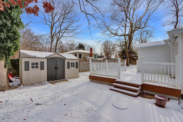 yard layered in snow featuring a storage unit and a deck