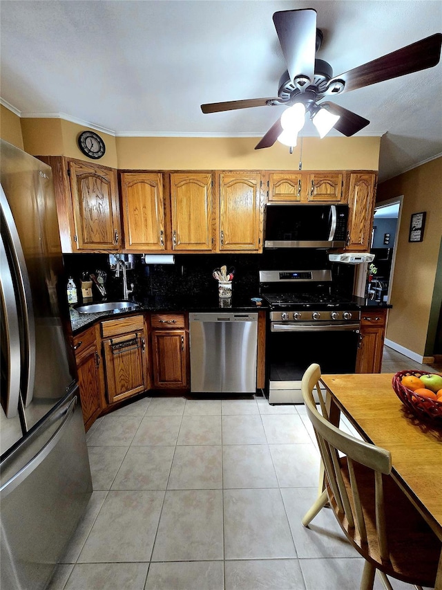 kitchen with appliances with stainless steel finishes, sink, light tile patterned floors, and decorative backsplash