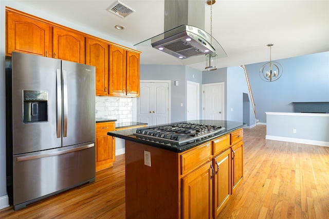 kitchen featuring stainless steel appliances, a kitchen island, pendant lighting, and light hardwood / wood-style floors