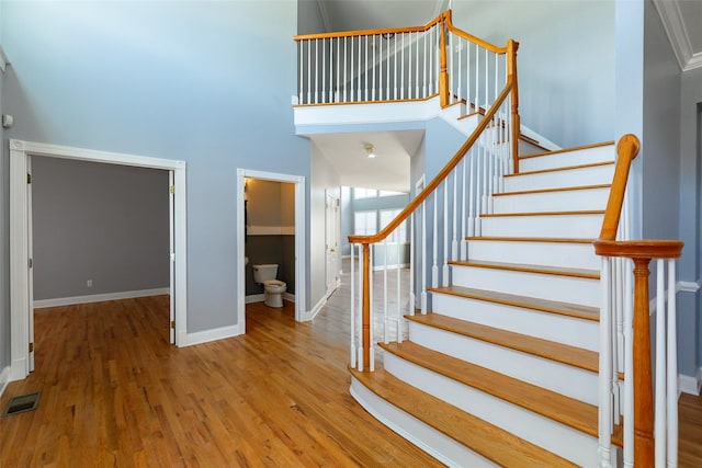 stairway featuring a towering ceiling and hardwood / wood-style floors