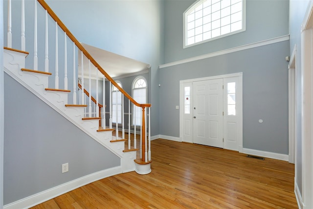 entryway with a towering ceiling, light hardwood / wood-style floors, and a wealth of natural light