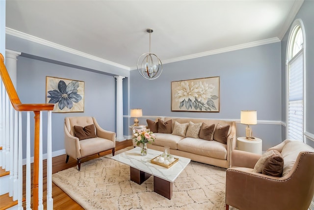 living room featuring hardwood / wood-style flooring, ornamental molding, a chandelier, and decorative columns