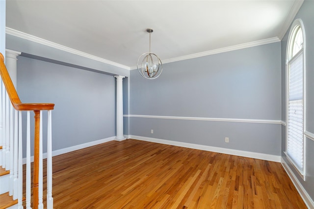 spare room featuring ornate columns, ornamental molding, a healthy amount of sunlight, and a chandelier