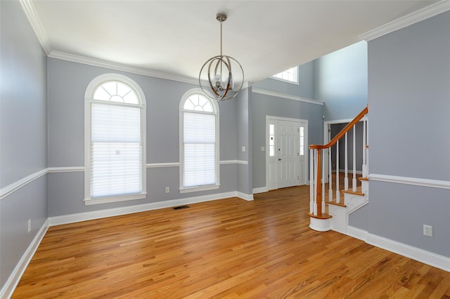 entrance foyer with ornamental molding, a chandelier, and light wood-type flooring