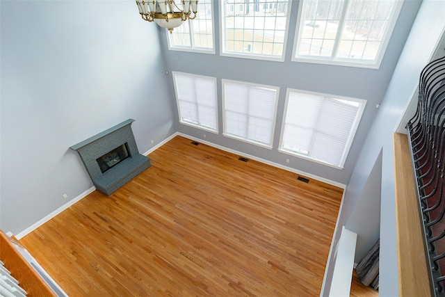 unfurnished living room with hardwood / wood-style flooring, a brick fireplace, and a healthy amount of sunlight