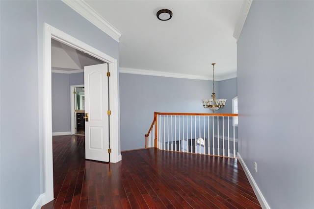 corridor featuring ornamental molding, wood-type flooring, and a chandelier