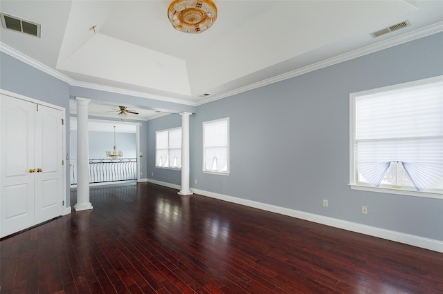 unfurnished living room with ornate columns, ceiling fan with notable chandelier, wood-type flooring, ornamental molding, and a raised ceiling