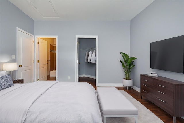 bedroom with ensuite bathroom, a walk in closet, dark hardwood / wood-style flooring, and a closet