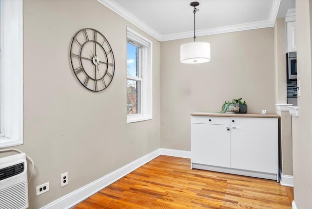 unfurnished dining area featuring ornamental molding, a wall mounted air conditioner, and light wood-type flooring