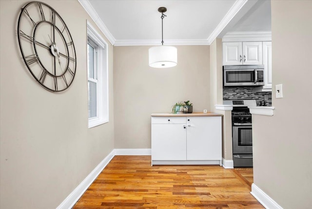 kitchen featuring white cabinets, decorative backsplash, hanging light fixtures, ornamental molding, and stainless steel appliances